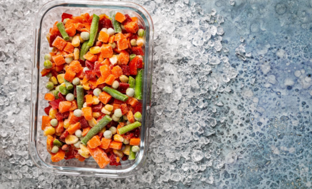 high-angle shot of frozen Mixed veggies in a glass container over crushed ice